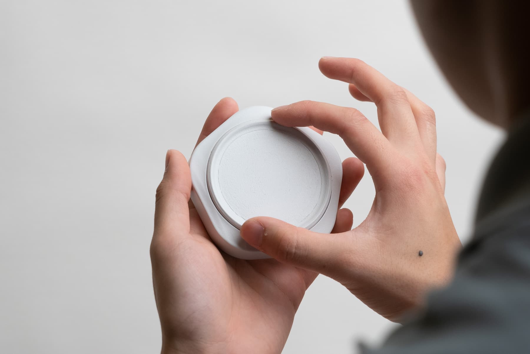 Someone holding a 3D-printed resin model of Budgetty in their left hand while turning the input dial with their right hand.